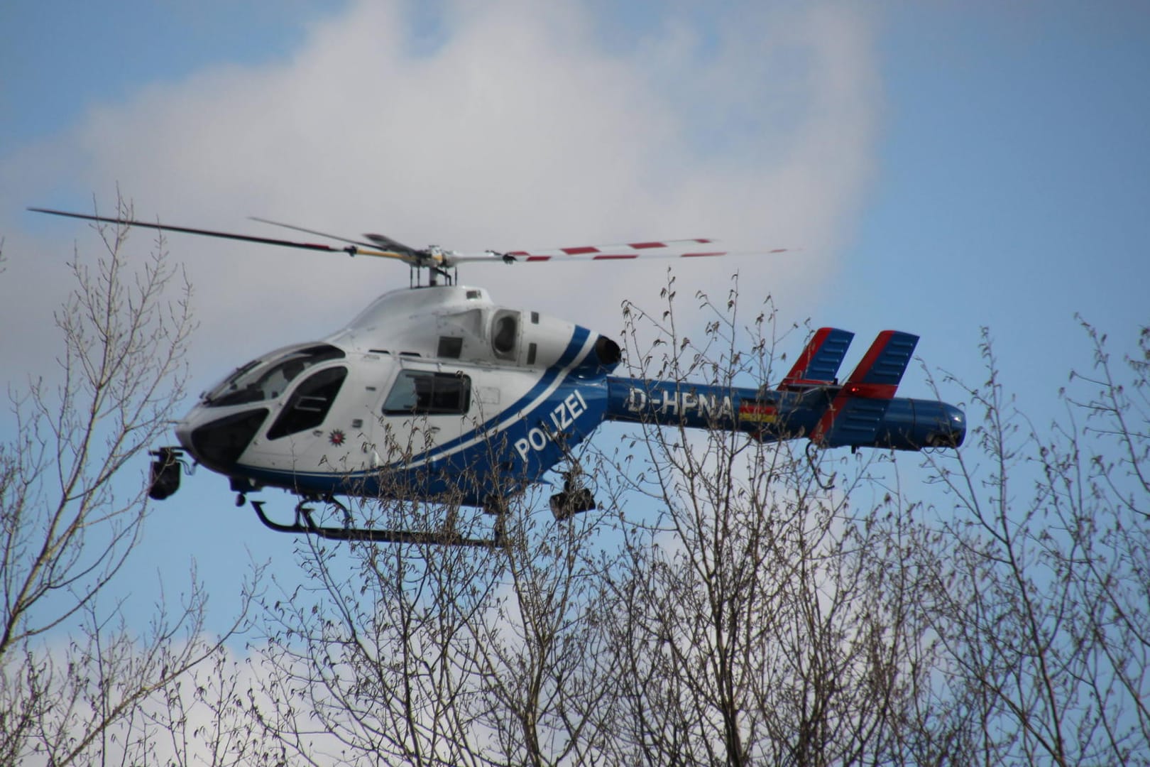 Ein Polizeihubschrauber über einem Waldstück (Symbolbild): Seit Anfang Februar gilt die 32-Jährige als vermisst.