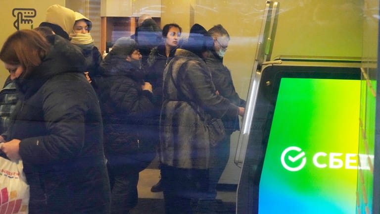 Russland, St. Petersburg: Menschen stehen in einer Schlange, um Geld von einem Geldautomaten in der Sberbank abzuheben.