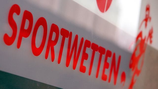 Werbung für Sportwetten klebt an der Schaufensterscheibe eines Wettbüros.