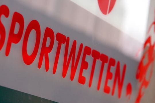 Werbung für Sportwetten klebt an der Schaufensterscheibe eines Wettbüros.