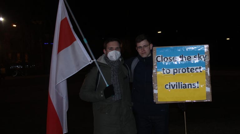 Konstantin Tkachuk (links) und Olexandr Pavlenko demonstrieren in München. Sie tragen die Flagge der belarussischen Opposition und ein Schild in den ukrainischen Farben.