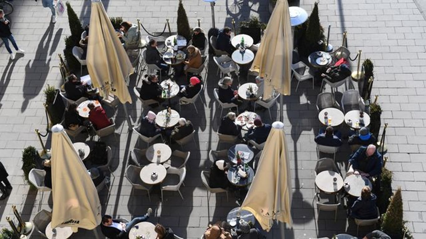 Gäste sitzen vor einem Café in der Sonne