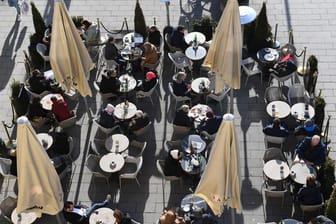 Gäste sitzen vor einem Café in der Sonne