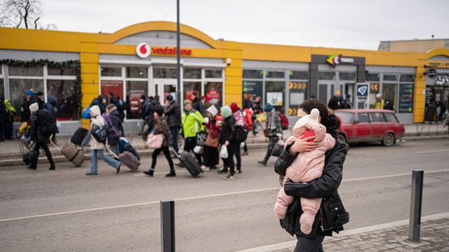 Eine Mutter mit ihrem Kind auf einer Straße in Lwiw während Luftalarm-Sirenen ertönen.