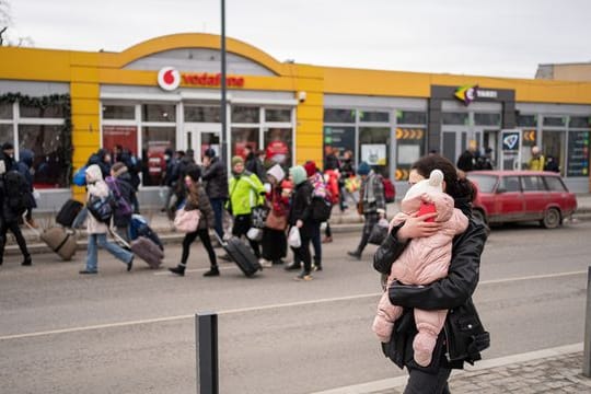 Eine Mutter mit ihrem Kind auf einer Straße in Lwiw während Luftalarm-Sirenen ertönen.