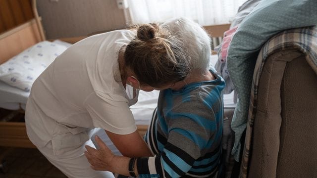 Eine Pflegefachkraft hilft einer Frau beim Aufstehen Eine Pflegefachkraft hilft einer Frau beim Aufstehen