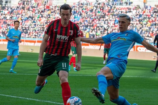 Augsburgs Michael Gregoritsch (l) und Freiburgs Nico Schlotterbeck kämpfen um den Ball.