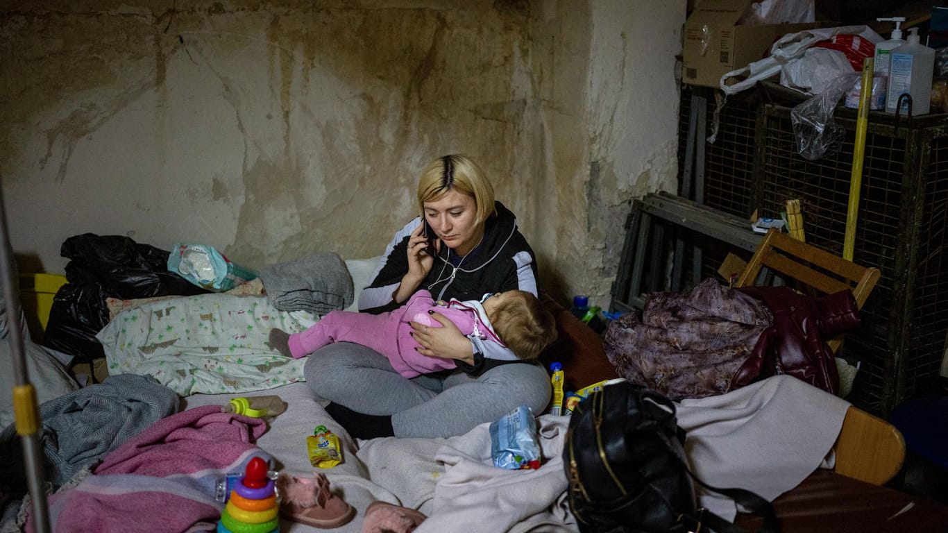 Eine Frau telefoniert, während sie ihr krankes Baby in einem als Bunker genutzten Keller des Okhmadet-Kinderkrankenhauses in den Armen hält: Die Ukraine hat das Internationale Rote Kreuz um Hilfe gebeten.