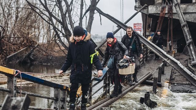 Zivilisten überqueren eine zuvor beschossene Brücke in der Stadt Irpin.