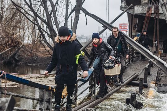 Zivilisten überqueren eine zuvor beschossene Brücke in der Stadt Irpin.