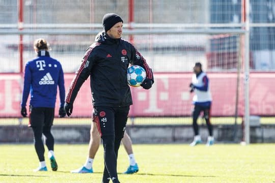 Bayern-Trainer Julian Nagelsmann geht mit einem Ball unter dem Arm über den Trainingsplatz an der Säbener Straße.