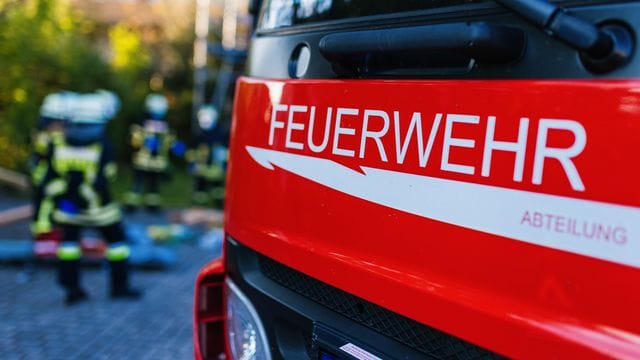 Einsatzkräfte der Feuerwehr stehen hinter einem Einsatzfahrzeug Einsatzkräfte der Feuerwehr stehen hinter einem Einsatzfahrzeug