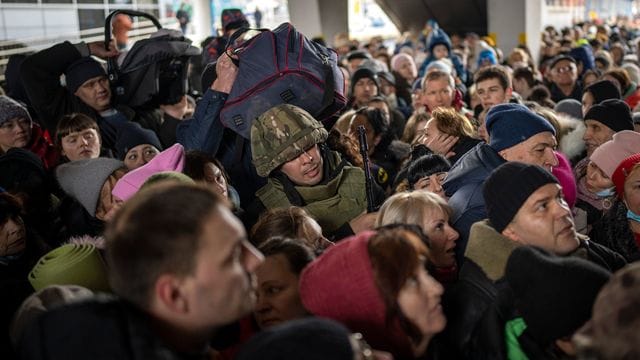 Ein ukrainischer Soldat versucht, die Menschenmenge aufzulösen, die am Bahnhof von Kiew in einen Zug nach Lwiw steigen will.