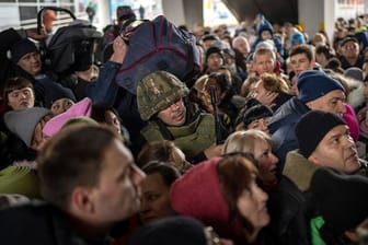 Ein ukrainischer Soldat versucht, die Menschenmenge aufzulösen, die am Bahnhof von Kiew in einen Zug nach Lwiw steigen will.