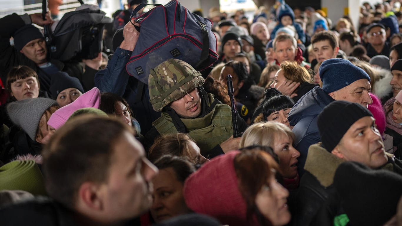 Ein ukrainischer Soldat versucht, die Menschenmenge aufzulösen, die am Bahnhof von Kiew in einen Zug nach Lwiw steigen will.