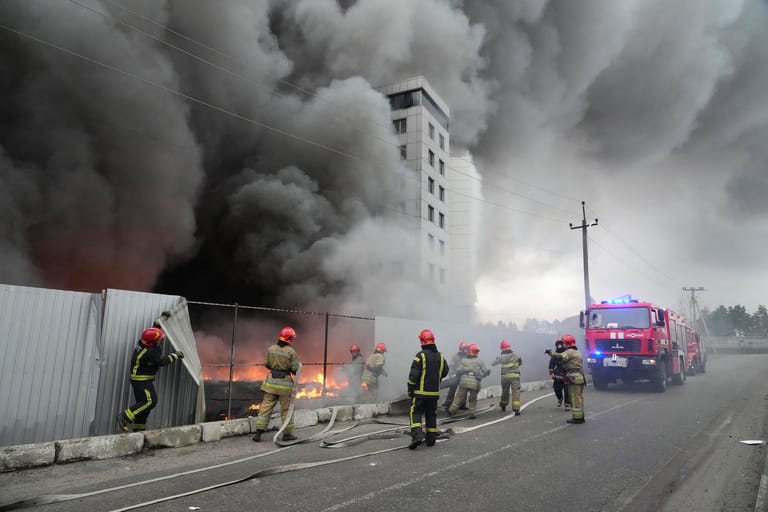 Einsatzkräfte löschen ein Feuer in Kiew nach einem Angriff.