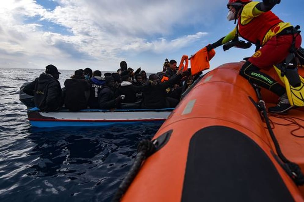 Mitglieder der NGO Open Arms helfen Migranten, die in einem Holzboot vor der Küste Libyens im Mittelmeer aufgebrochen sind.