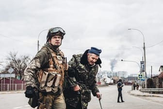 Ein ukrainischer Soldat hilft einem älteren Mann, die Straße zu überqueren.