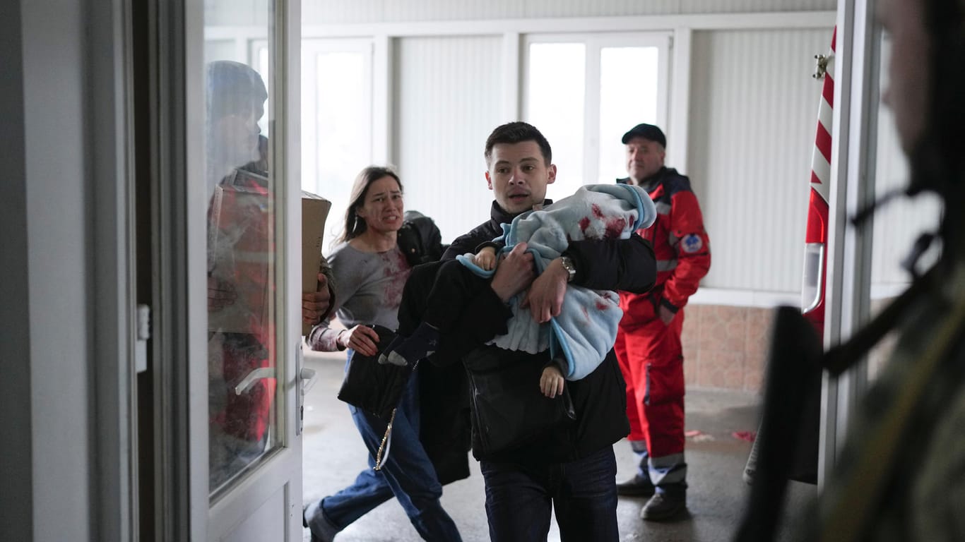 Marina Yatsko (l.) läuft hinter ihrem Freund Fedor her. Er trägt ihren 18 Monate alten Sohn Kirill, der beim Beschuss getötet wurde, als sie am Freitag in einem Krankenhaus in Mariupol ankommen.