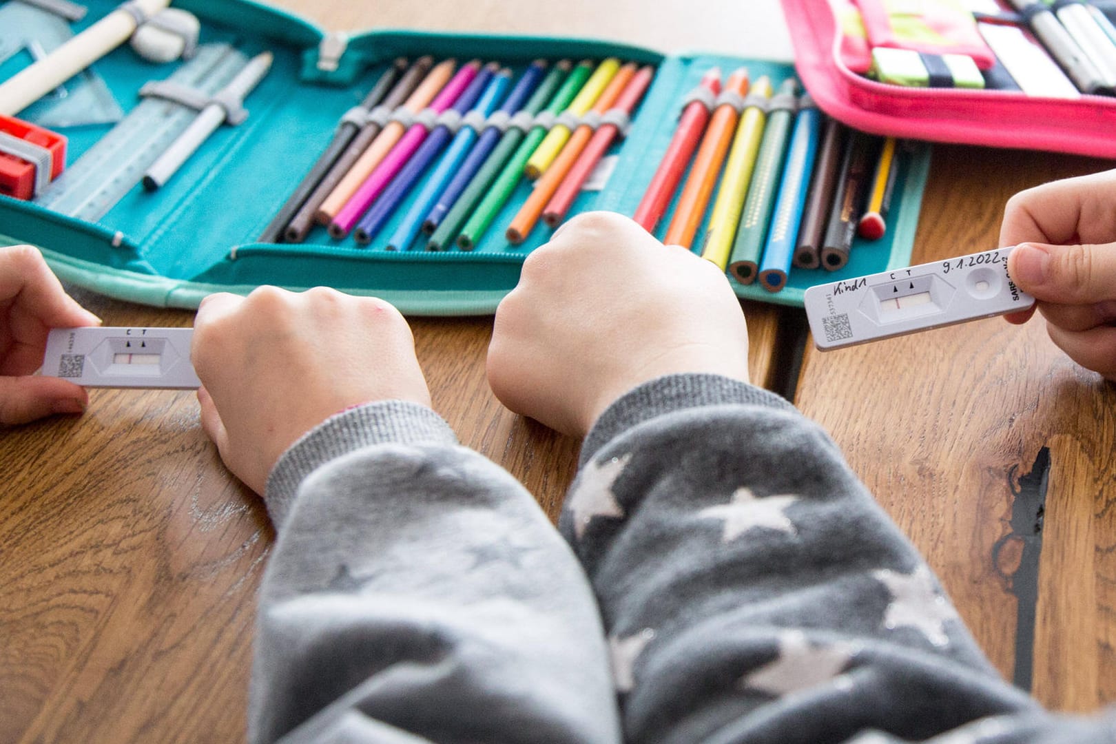 Zwei Schulkinder halten Corona-Tests in der Hand (Archivbild): In Schulen in Niedersachsen wird nun weniger getestet.