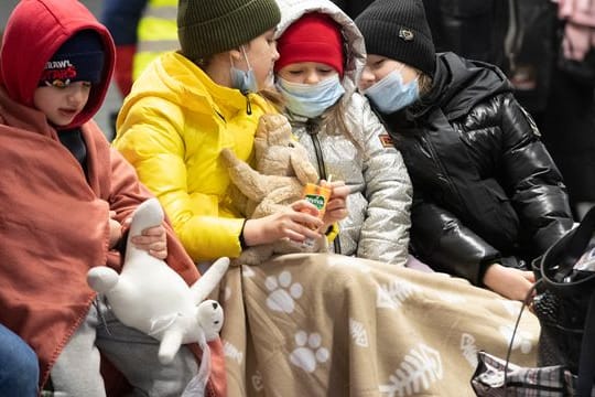 In Decken gehüllt sitzen diese Kinder aus dem ukrainischen Kriegsgebiet auf einer Bank im Berliner Hauptbahnhof.