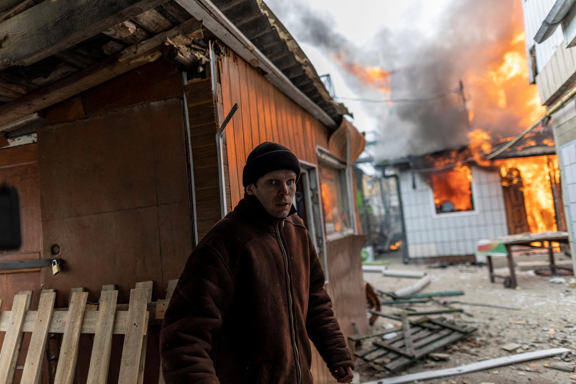 24 Kilometer von Kiew entfernt steht ein Einwohner vor einem brennenden Wohnhaus.