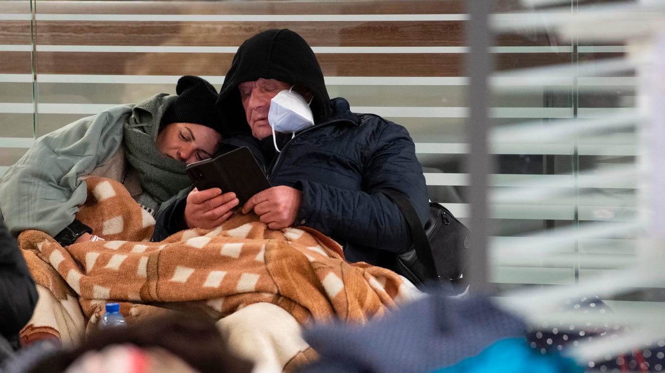 Zwischen Reisetaschen sitzen die beiden Geflüchteten auf dem Boden im Berliner Hauptbahnhof: Die Zahl der Geflüchteten steigt immer mehr an.