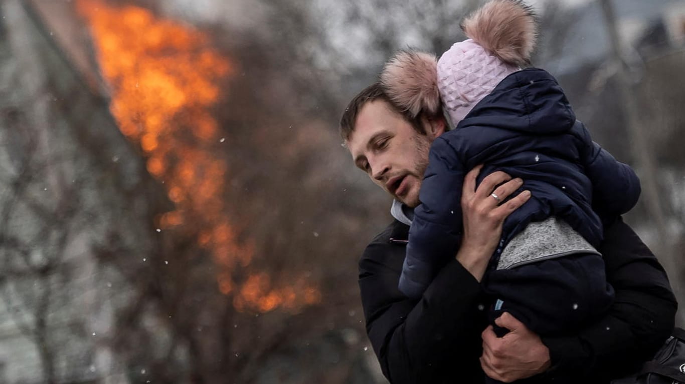 Ein Mann flieht mit einem Kind aus Irpin: Die russischen Truppen setzten eingekesselte Städte unter Beschuss.