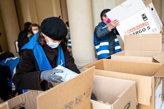 Freiwilige Helfer packen am Berliner Humboldt Forum Hilfsgüter in Kisten.