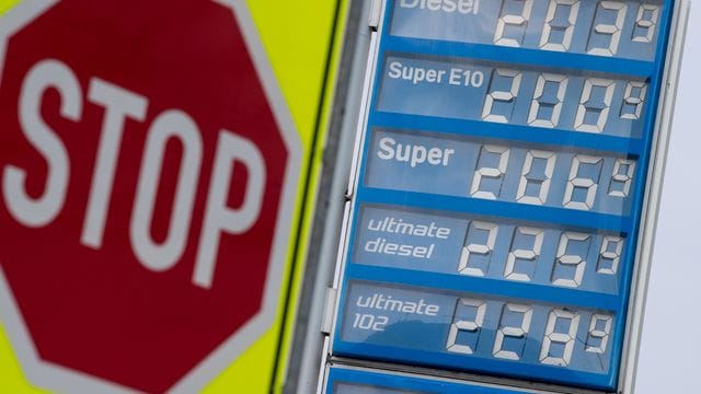 Ein Stoppchild steht neben einer Anzeigentafel von Preisen für Diesel und Benzin an einer Tankstelle. Ein Stoppchild steht neben einer Anzeigentafel von Preisen für Diesel und Benzin an einer Tankstelle.