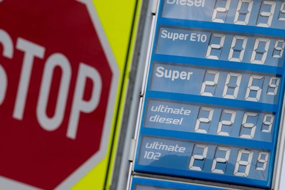 Ein Stoppchild steht neben einer Anzeigentafel von Preisen für Diesel und Benzin an einer Tankstelle.