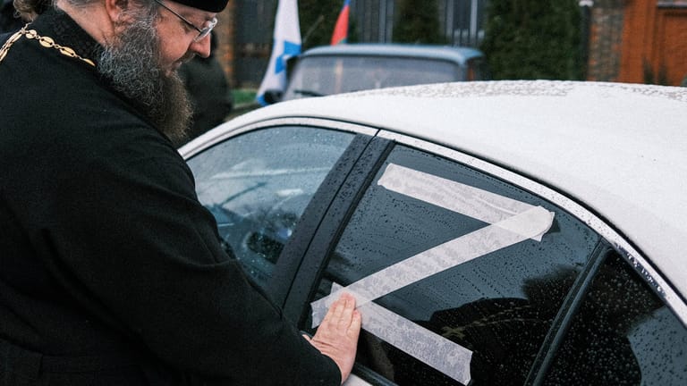 Ein orthodoxer Priester in Krasnodar klebt ein "Z" auf ein Auto: Immer mehr Menschen in Russland zeigen sich öffentlich mit dem Kriegssymbol.