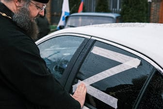 Ein orthodoxer Priester in Krasnodar klebt ein "Z" auf ein Auto: Immer mehr Menschen in Russland zeigen sich öffentlich mit dem Kriegssymbol.