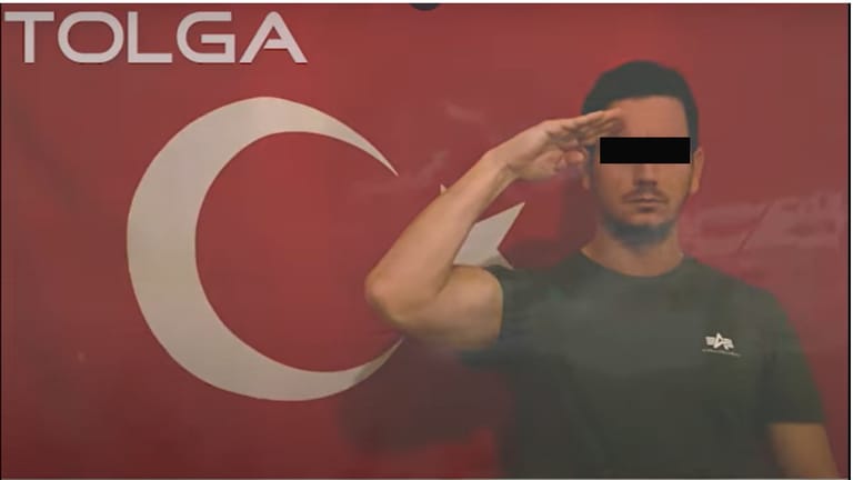 Unter dem Künstlernamen Tolga zeigt sich ein Berliner Polizist in einem Musikvideo salutierend vor einer türkischen Flagge.