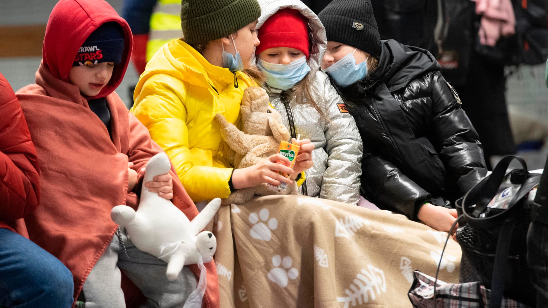 In Decken gehüllt sitzen diese Kinder aus dem ukrainischen Kriegsgebiet auf einer Bank im Berliner Hauptbahnhof: Täglich kommen Tausende ukrainische Flüchtlinge in Berlin an.