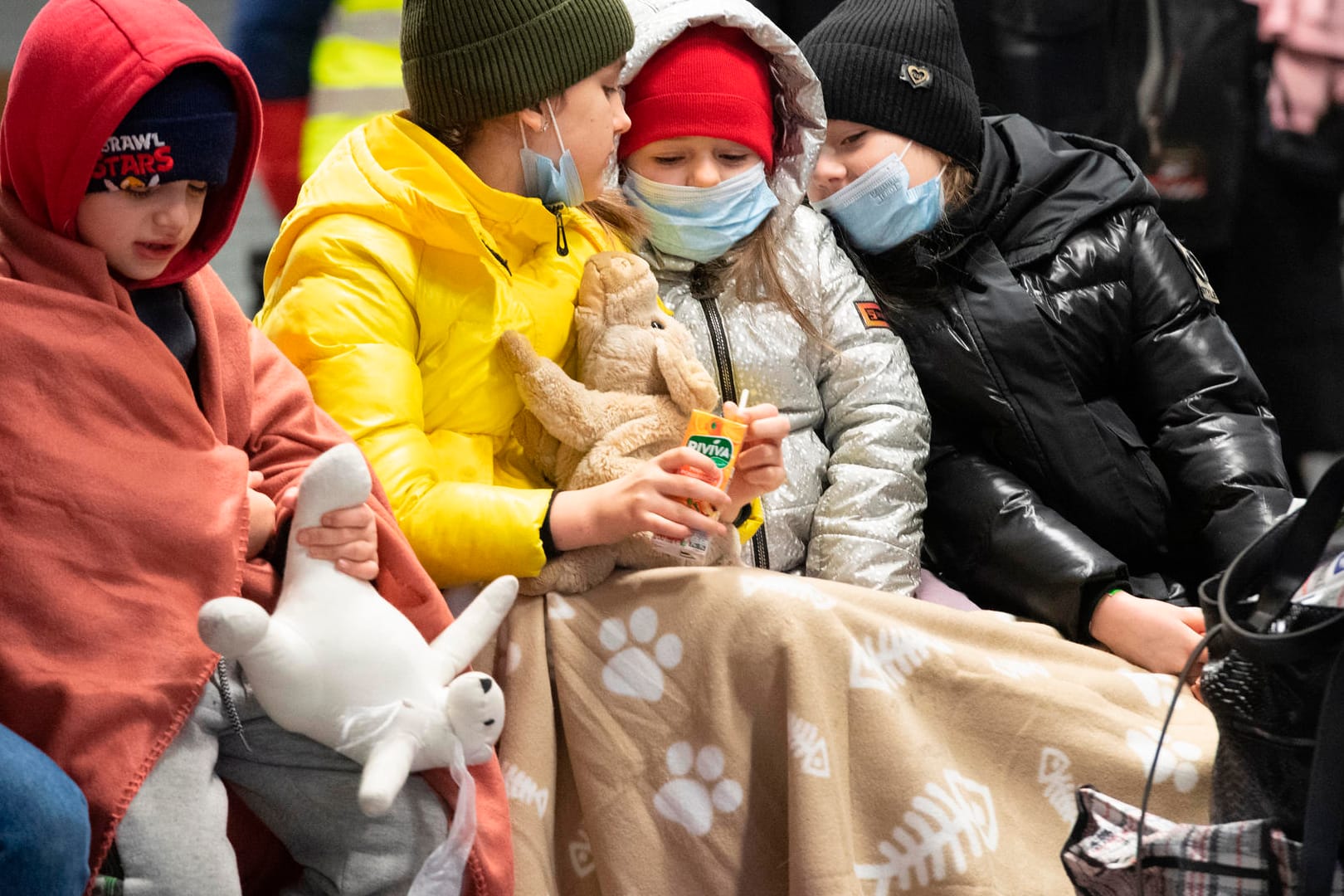 In Decken gehüllt sitzen diese Kinder aus dem ukrainischen Kriegsgebiet auf einer Bank im Berliner Hauptbahnhof: Täglich kommen Tausende ukrainische Flüchtlinge in Berlin an.