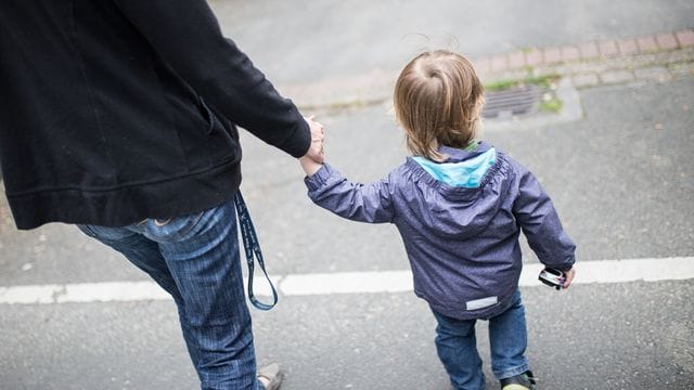 Eine Mutter hält ihren Sohn an der Hand.