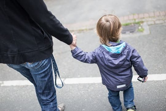 Eine Mutter hält ihren Sohn an der Hand.