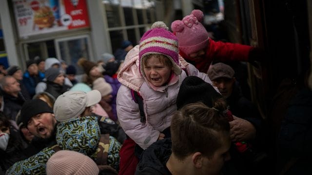 Menschen tragen ihre Kinder und versuchen am Bahnhof von Kiew, in einen Zug nach Lwiw zu steigen. Menschen tragen ihre Kinder und versuchen am Bahnhof von Kiew, in einen Zug nach Lwiw zu steigen.