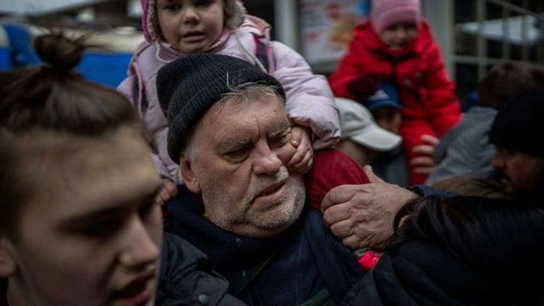 Ein Mädchen hält sich am Gesicht ihres Großvaters fest, während sie am Bahnhof von Kiew versuchen, in einen Zug nach Lwiw zu steigen.