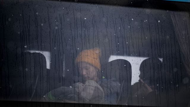 Eine Frau, die aus der Ukraine geflohen ist, hält ein Baby im Arm, während sie in einem Bus an der rumänisch-ukrainischen Grenze sitzt. Eine Frau, die aus der Ukraine geflohen ist, hält ein Baby im Arm, während sie in einem Bus an der rumänisch-ukrainischen Grenze sitzt.