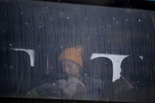 Eine Frau, die aus der Ukraine geflohen ist, hält ein Baby im Arm, während sie in einem Bus an der rumänisch-ukrainischen Grenze sitzt.