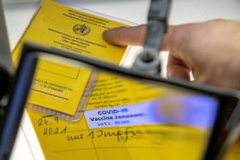 Gefälschte Impfpässe unter einer Lupe (Symbolbild).