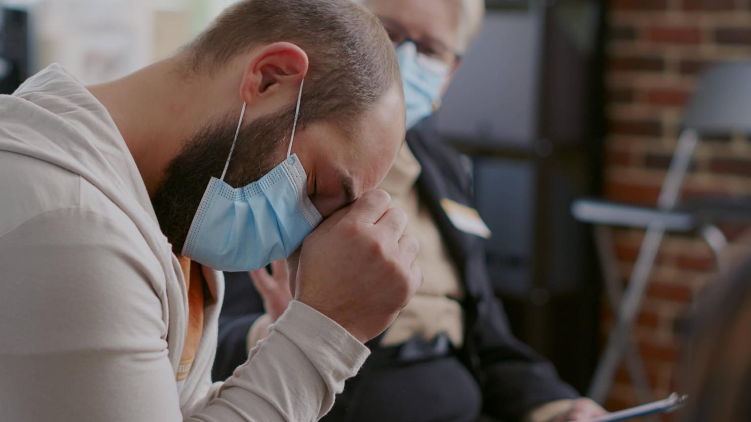 Ein Mann in einer Selbsthilfegruppe für Long-Covid-Patienten legt den Kopf in die Hand: Die Krankheit schädigt Hirnareale, die Emotionen und Gedächtnis steuern.