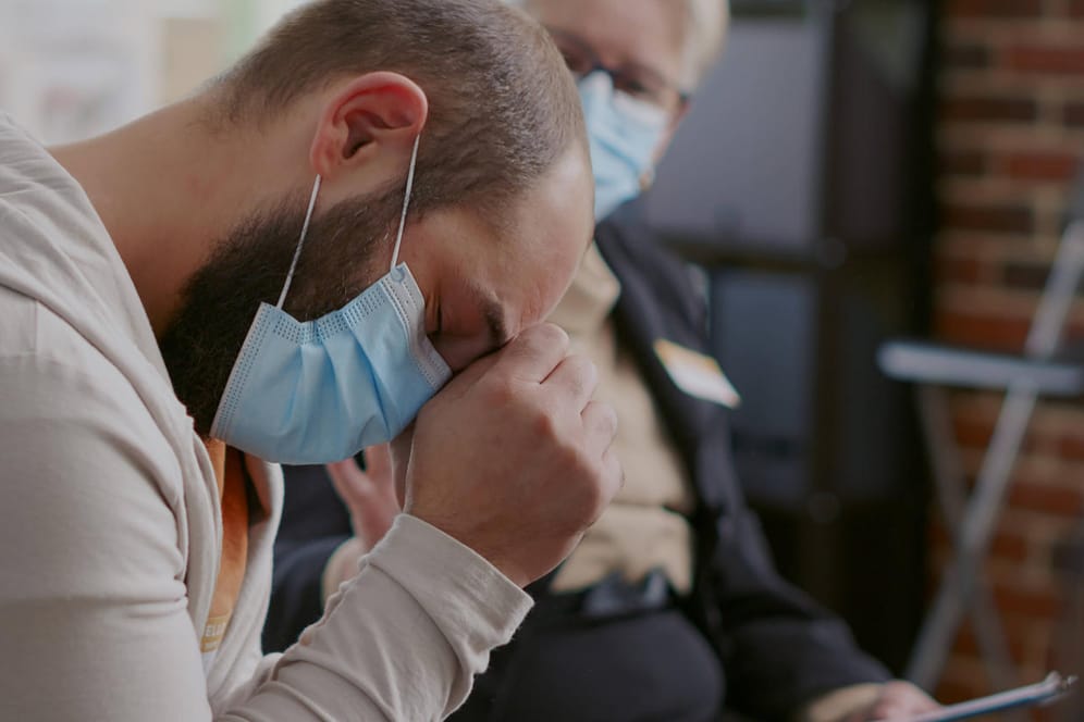 Ein Mann in einer Selbsthilfegruppe für Long-Covid-Patienten legt den Kopf in die Hand: Die Krankheit schädigt Hirnareale, die Emotionen und Gedächtnis steuern.
