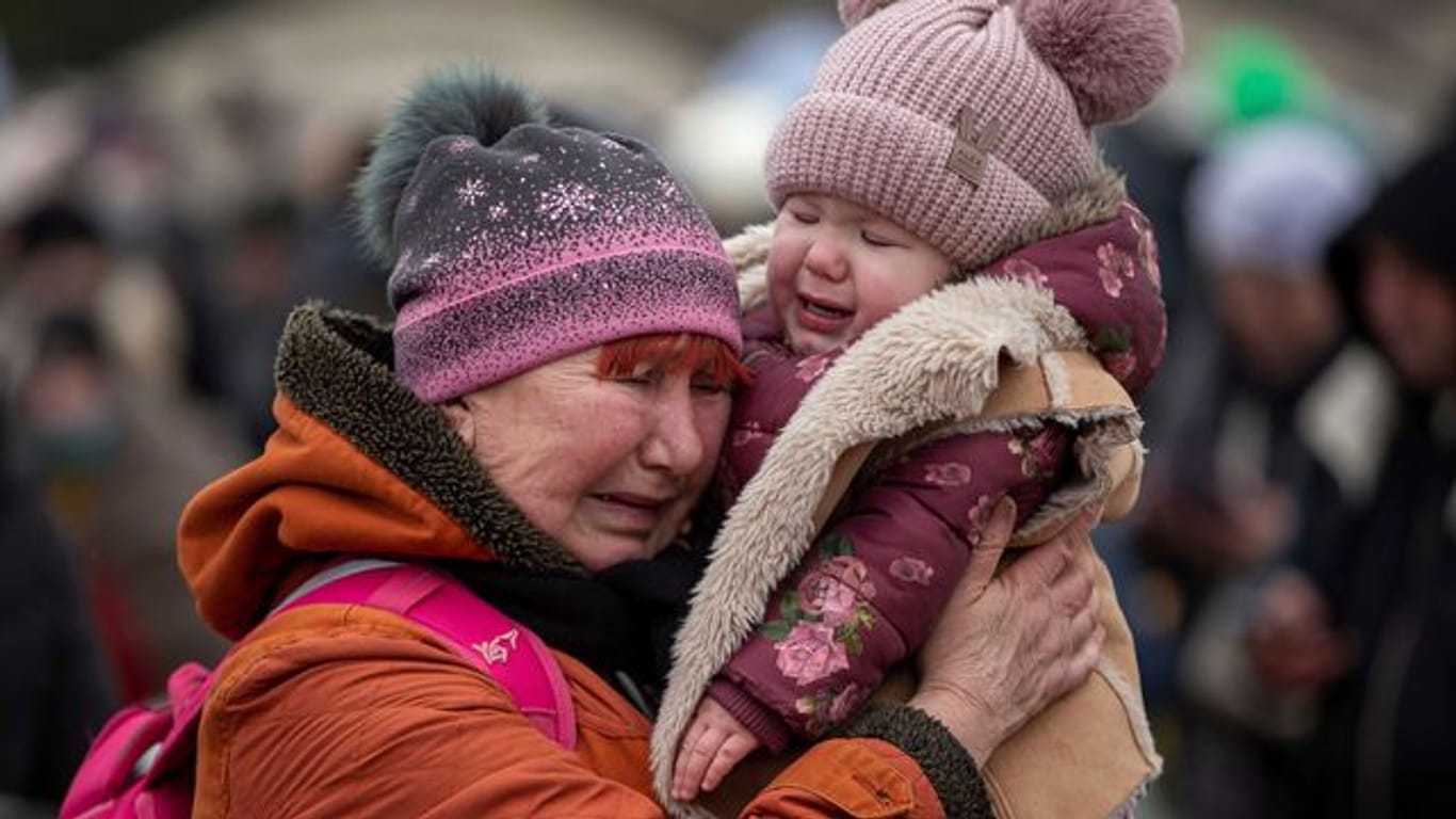 Eine weinende Frau mit einem Kind im Arm am Grenzübergang im polnischen Medyka.
