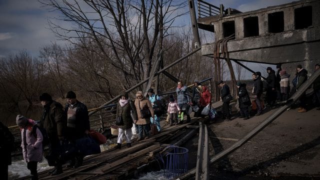 Auf der Flucht vor russischen Angriffen überqueren diese Ukrainer den Fluss Irpin unter einer zerstörten Brücke.