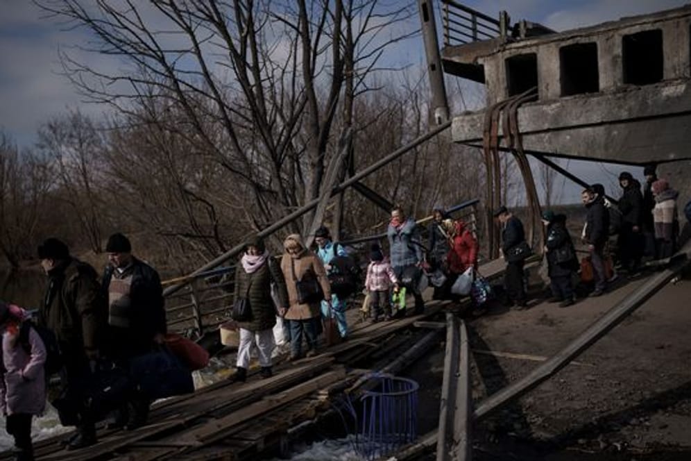 Auf der Flucht vor russischen Angriffen überqueren diese Ukrainer den Fluss Irpin unter einer zerstörten Brücke.