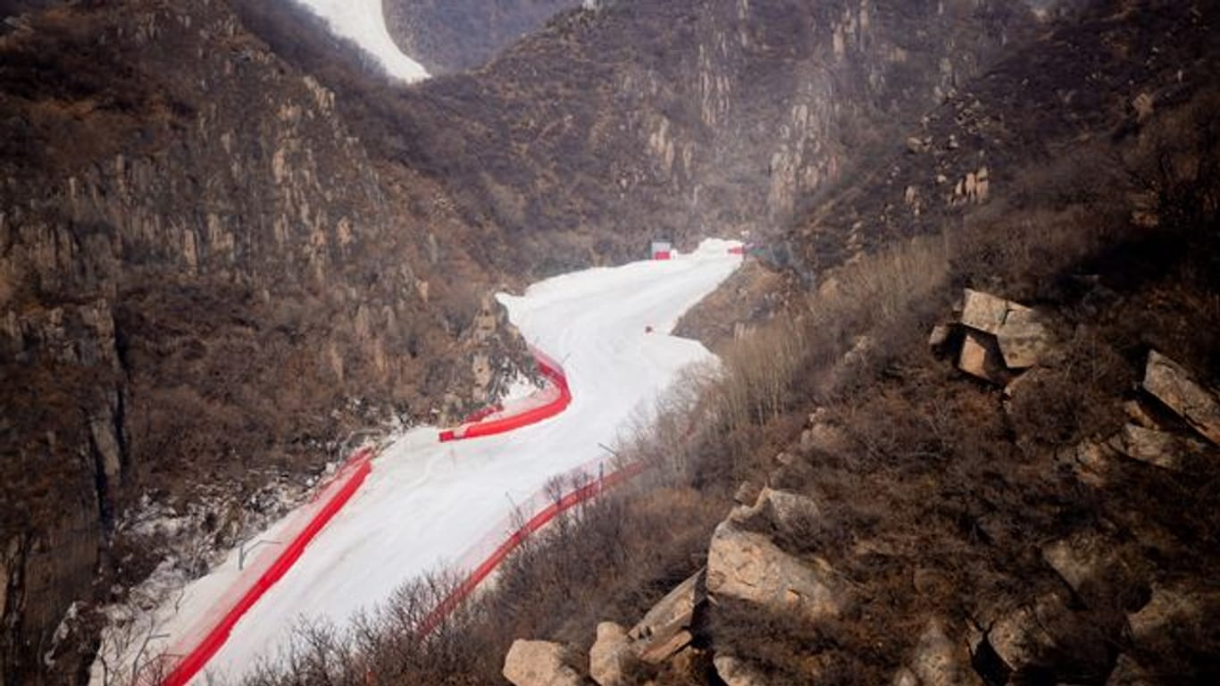 Eine Kunstschneepiste im Nationalen Ski-Alpin-Zentrum in Yanqing in der ansonsten schneefreien Landschaft.
