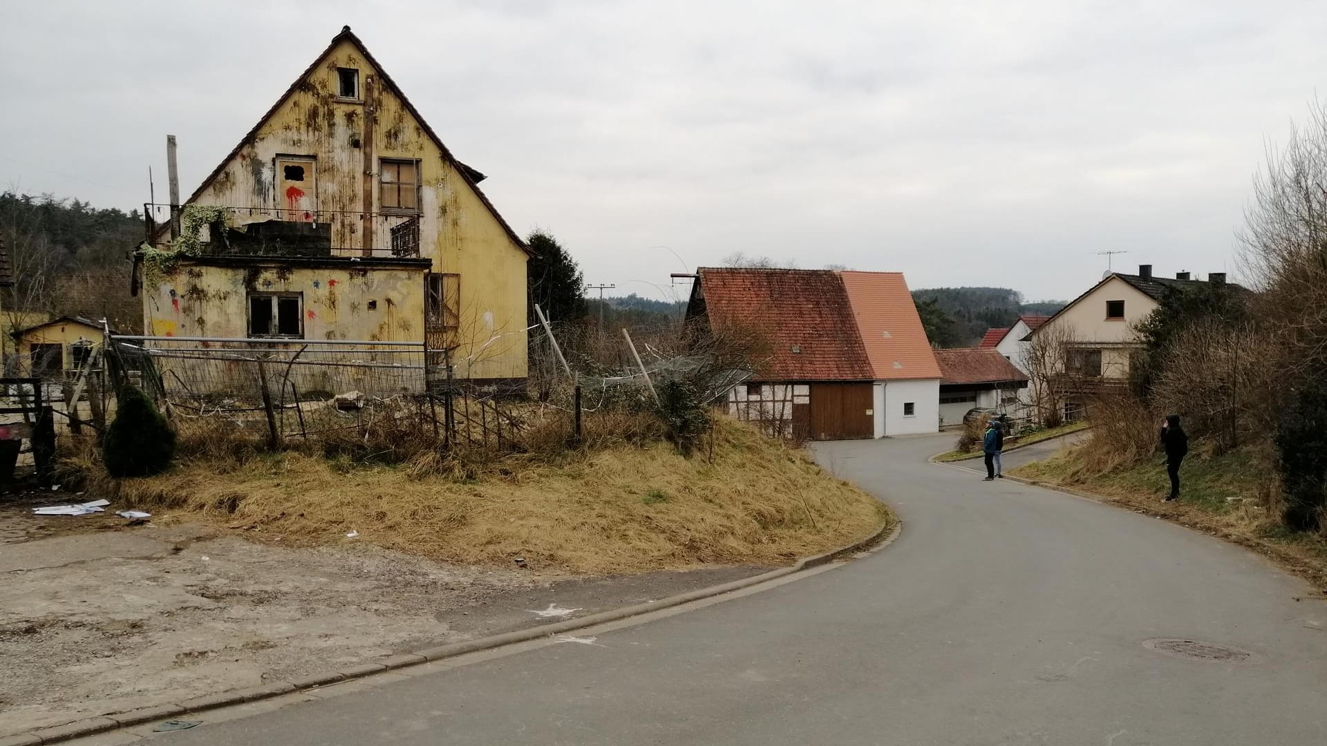 Personen stehen vor dem leeren Haus.